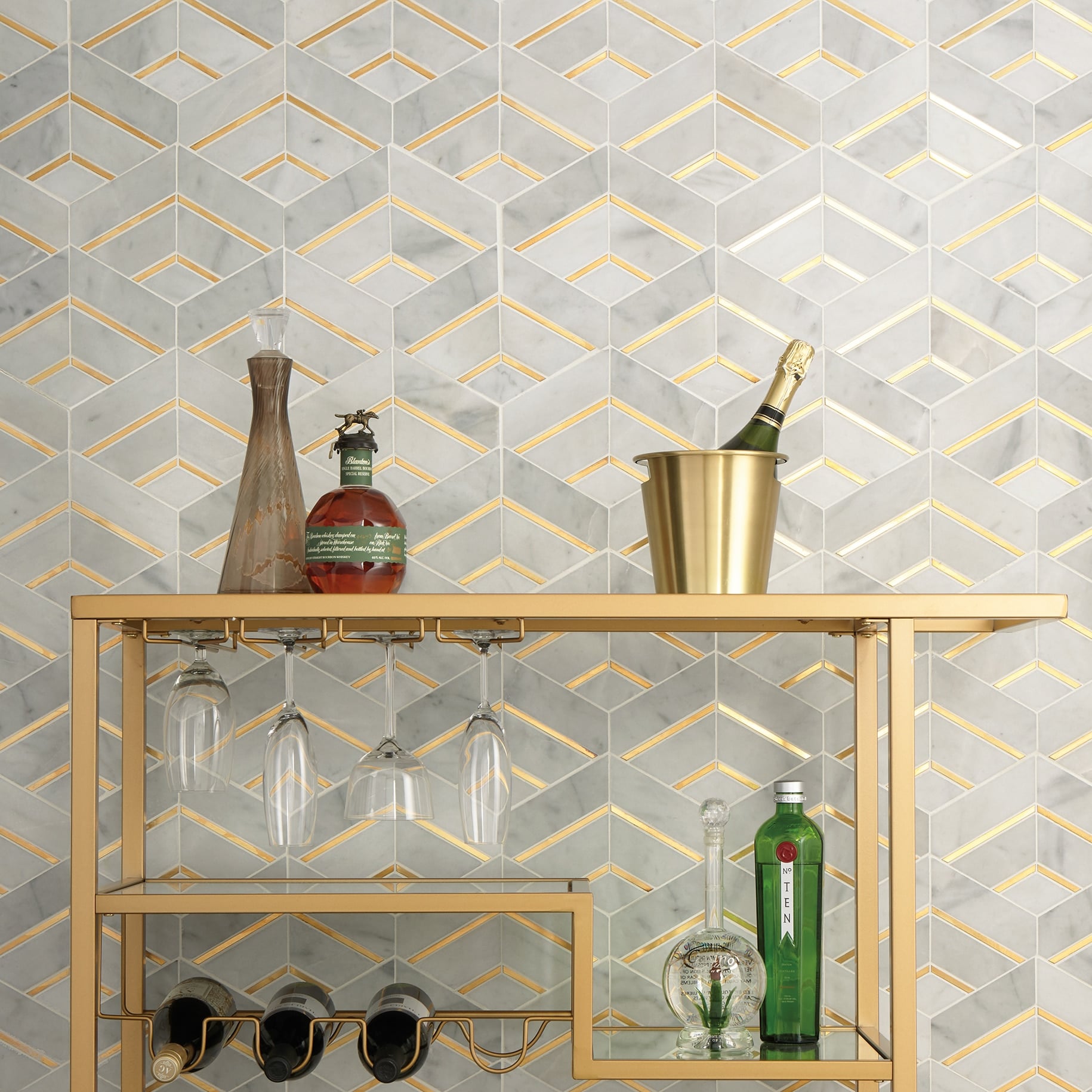 Wet bar with bookmatched marble wall, brass shelving, and glass cabinetry